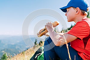 Smiling boy portrait with huge long baguette sandwich on the mountain path food break point
