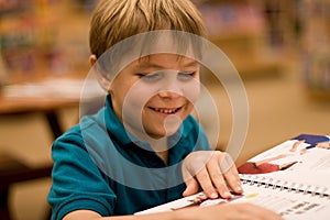 Smiling boy reads a book at libary photo