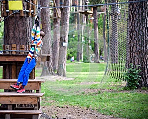Smiling boy rides a zip line. happy child on the zip line. The kid passes the rope obstacle course