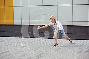 Smiling boy running, playing in town, city in summer day