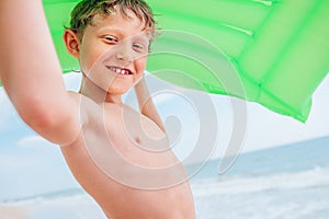 Smiling boy sea portrait with green air swiming mattress photo