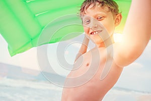 Smiling boy sea portrait with green air swiming mattress