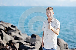 Smiling boy showing thumb up on sea background