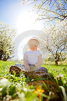 Smiling boy sits on a grass under sun beams