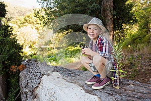 Smiling boy sitting on the tree trunk in the forest