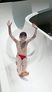 Smiling boy slides a waterslide photo