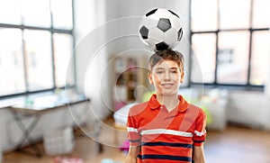 smiling boy with soccer ball on his head at home