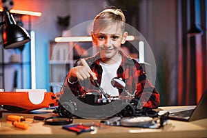 Smiling boy soldering remote controlled toy car