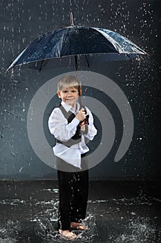 Smiling boy standing under umbrella in rain