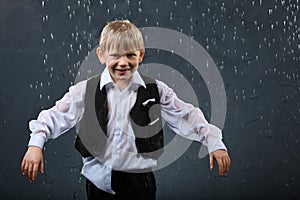 Smiling boy stands in rain