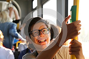 Smiling boy with stylish glasses travels by tram