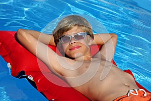 Smiling boy with sun glasses relaxing on airbed
