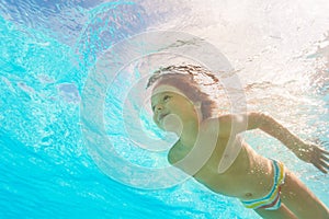 Smiling boy swimming under crystal-clear water