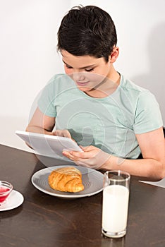 Boy using digital tablet during breakfast in kitchen