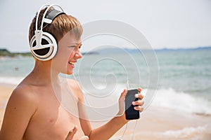Smiling boy using a smartphone on the beach