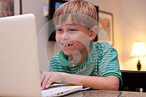 Smiling boy using white laptop