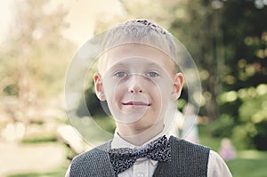 Smiling boy in vest and bowtie looking at camera