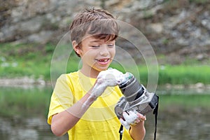 Smiling boy washes a SLR camera