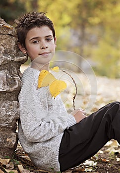 Smiling boy with yellow leaves in hands