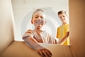 Smiling Boys Unpacking Box in New House