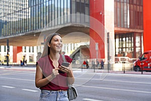 Smiling Brazilian woman hail a vehicle using mobile app waiting for taxi or uber on Paulista Avenue, Sao Paulo, Brazil photo