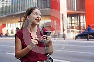 Smiling Brazilian woman hail a vehicle using mobile app waiting for taxi or uber on Paulista Avenue, Sao Paulo, Brazil photo