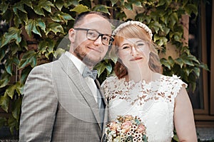 Smiling bridal couple in front of green foliage