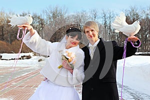 Smiling bride and groom hold white doves