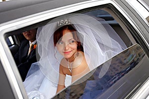 Smiling bride with groom in wedding limo photo