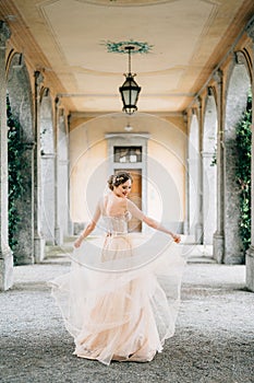 Smiling bride in a wedding dress whirls on an old pillared terrace. Lake Como