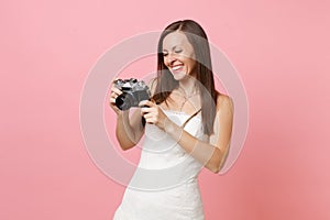 Smiling bride woman in wedding dress holding looking on retro vintage photo camera choosing staff photographer