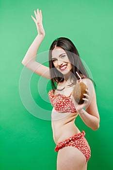 Smiling Brunette in Bright Swimsuit with Tropical Cocktail in Hands on Green Background.