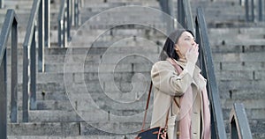 Smiling brunette caucasian woman waving to someone and sending air kiss. Young beautiful business lady standing on stairs