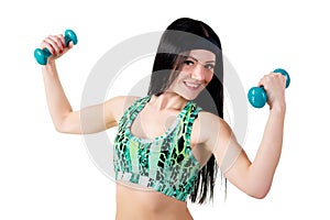 Smiling brunette girl with long hair in a green sports shirt holding a dumbbell