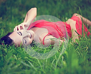 Smiling brunette girl lying in green summer grass