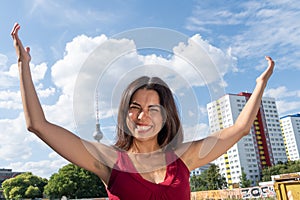 Smiling brunette girl with raised arms, outdoors