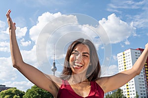 Smiling brunette girl with raised arms, outdoors