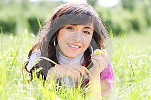 Smiling brunette in grass with dandelion