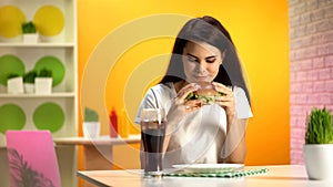 Smiling brunette lady holding delicious burger, fast food restaurant, temptation