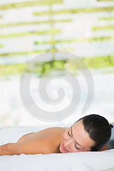 Smiling brunette lying on massage table with eyes closed