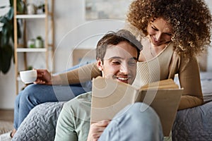 Smiling brunette man reading book and