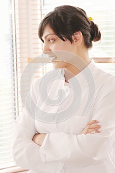 Smiling brunette in smock looking to window photo