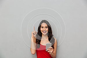 Smiling brunette woman in casual clothes holding smartphone