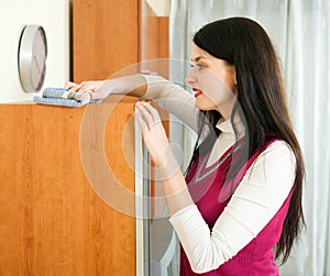 Smiling brunette woman cleaning wooden furiture