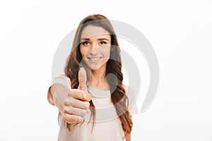 Smiling brunette woman in t-shirt showing thumb up