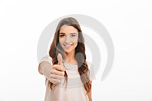 Smiling brunette woman in t-shirt showing thumb up at camera