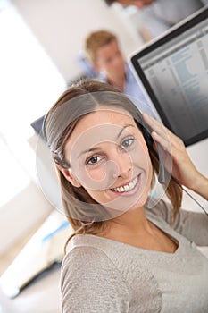 Smiling brunette woman talking on headset from office