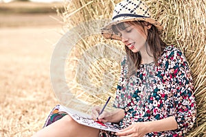 Smiling brunnete coloring in the village on the hay