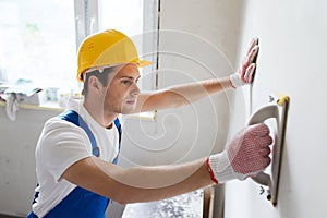 Smiling builder with grinding tool indoors