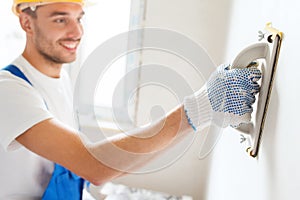 Smiling builder with grinding tool indoors